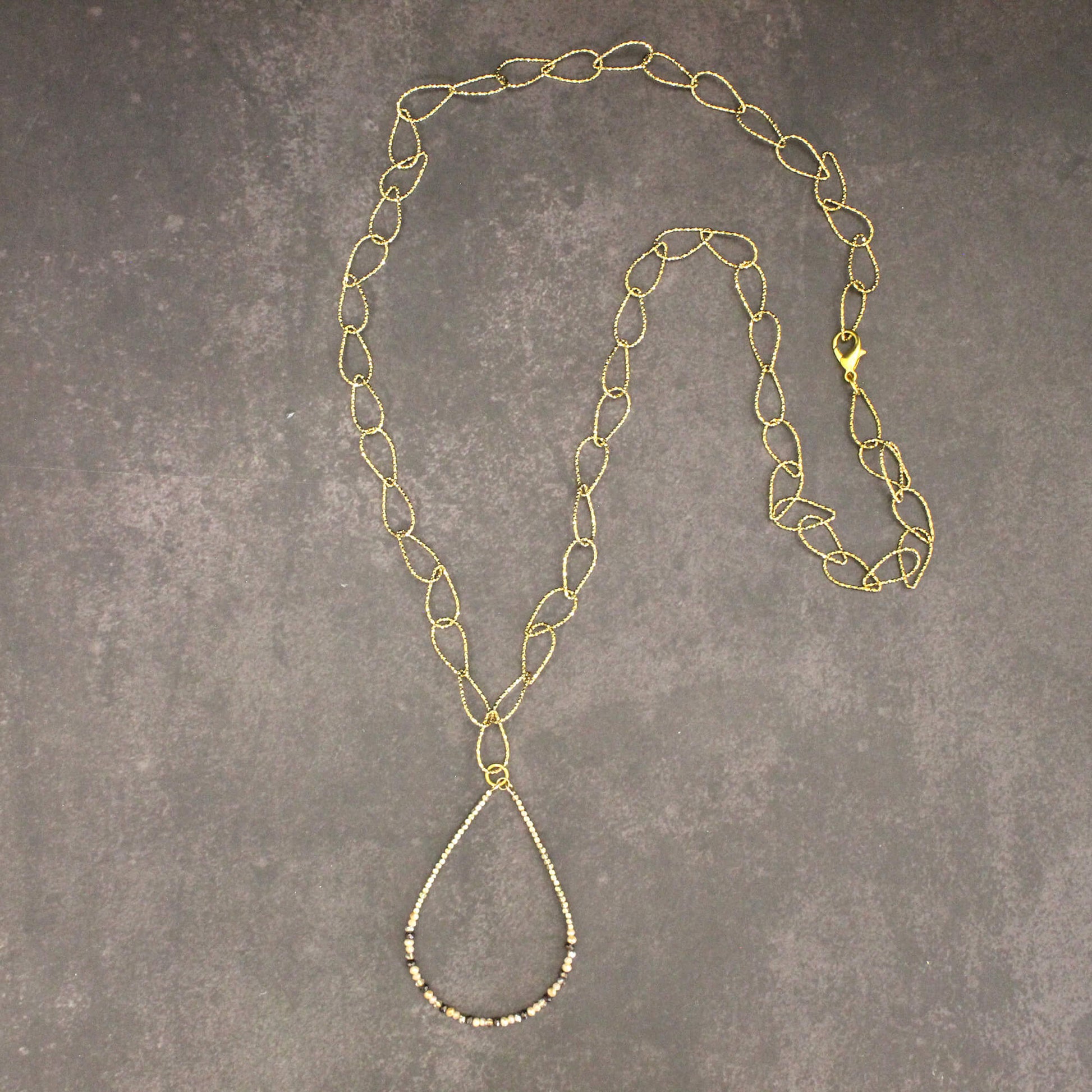 Gold chain necklace on a gray textured surface