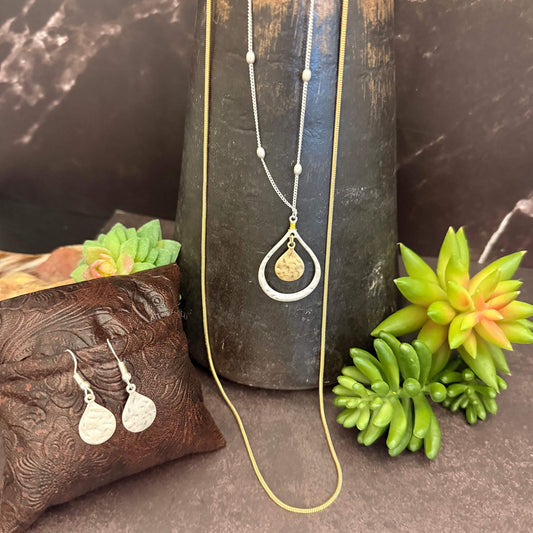 Jewelry set with necklace and earrings on a dark surface with succulents