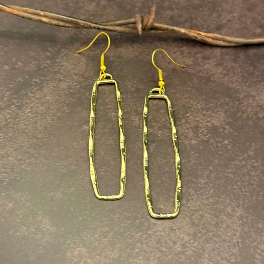 Gold Dangle Rectangle earrings on a textured brown surface