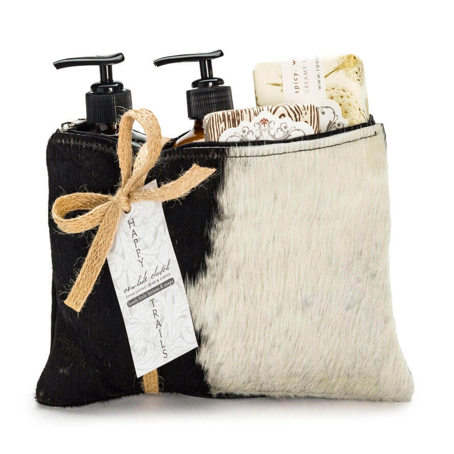 Black and white cowhide pouch with skincare products and a bow on a white background