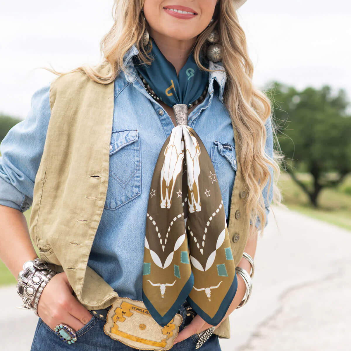 Model wearing Hooked Longhorn Western Silk Scarf with cattle brand design, outdoors in Western attire, showcasing ranch life style.