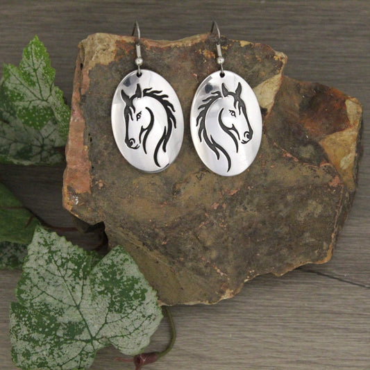 These Equine oval silver earrings dangle and etched with a stunning horsehead. Show your love for all things horses with these cute cowgirl western earrings. Oval pendant measures 1-1/2" by 1" on hypo-allergenic wire hooks.