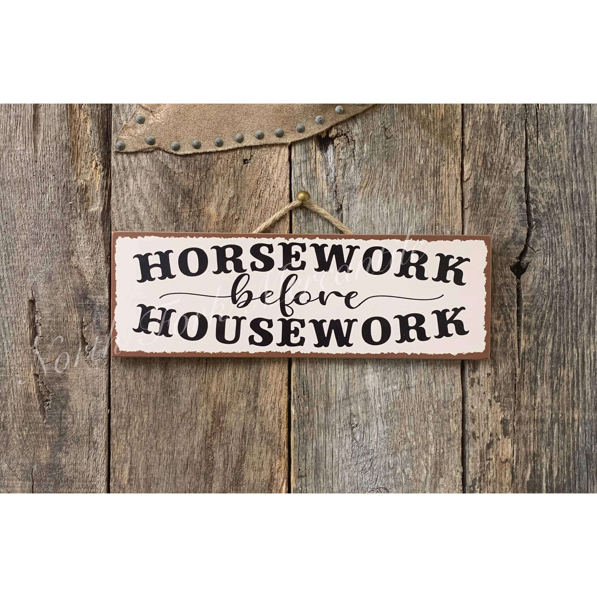 Decorative sign with 'Horsework before Housework' text on a wooden background