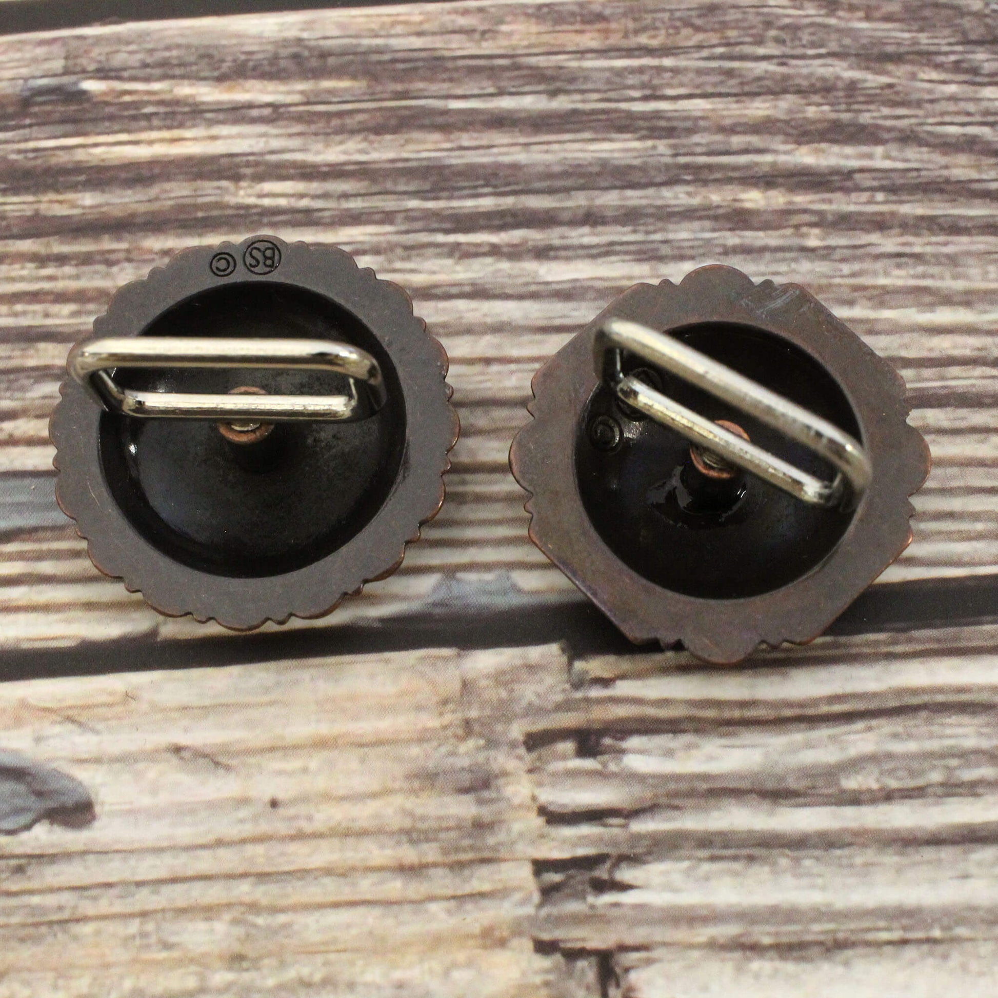 Pair of black metal earrings on a wooden surface