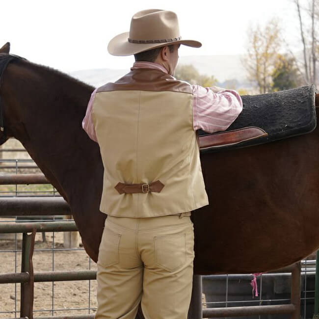 This classic style vest is inspired by the original “Duke Vest” that was made popular by John Wayne. The vest is made of quality leather in the front, back yoke and back adjustable belt and a canvas back. Designed for rugged good looks and classic western style. This handsome vest features a notched lapel, four welt pockets and finished with 5 antler buttons. What a terrific way to honor the Duke and look great at the same time! Made in the USA.