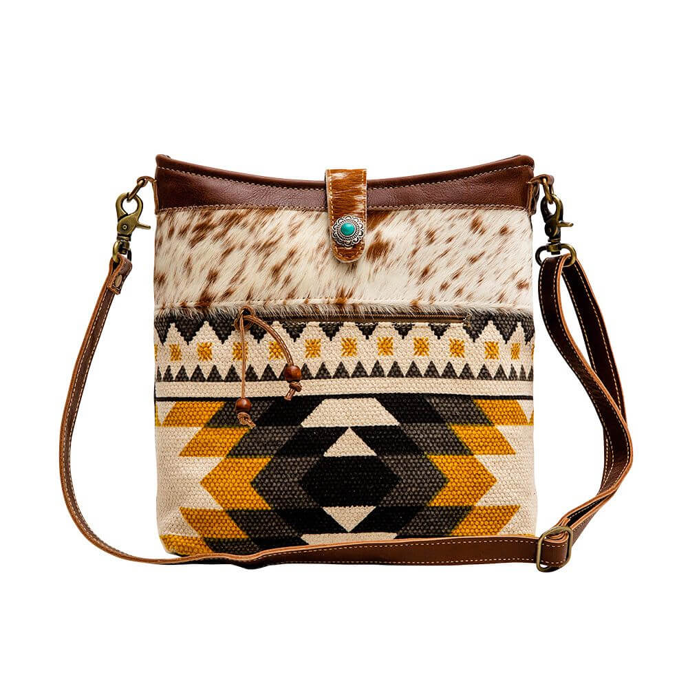 This cowgirl purse features cowhide and genuine leather with a striking canvas in black and yellow color palette with a 22" shoulder strap. Measuring 13"x3"x11" Made in India