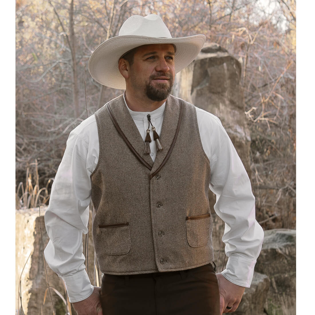 The fashionable look of this western wool vest is the perfect addition to your western outfit. This vest has simple style with faux leather trim on the shawl collar and pockets. The back of the vest is made of satin polyester that compliments the Herringbone Wool. Look like the best-dressed cowboy in the West! Fully Lined. Dry clean Recommended. Made in USA.