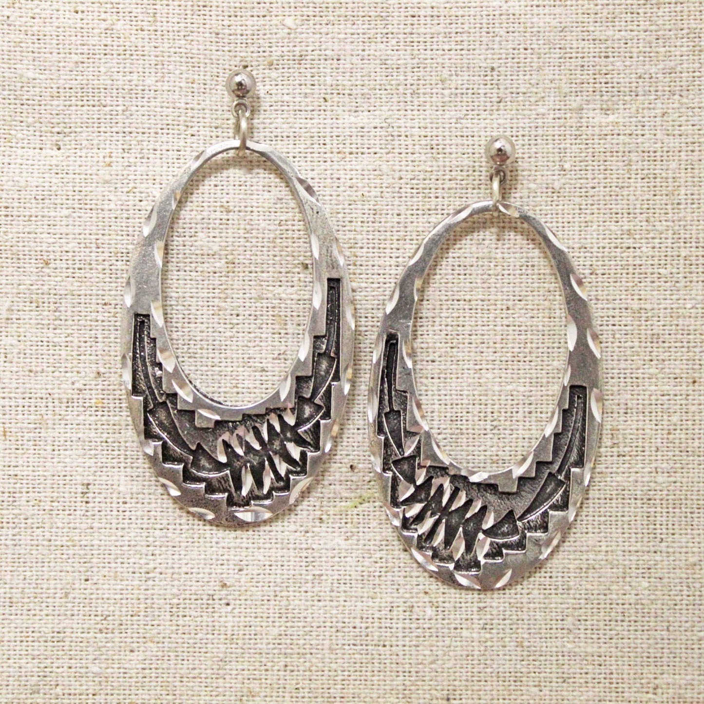 These beautiful and elegant earrings are made of a pewter and feature an oval shape with arrow design. Each piece is handmade and hand finished with diamond cuts. The sparkly cuts give each piece a unique dazzling sparkle. Approximately 2" long by 1" wide. Made in USA