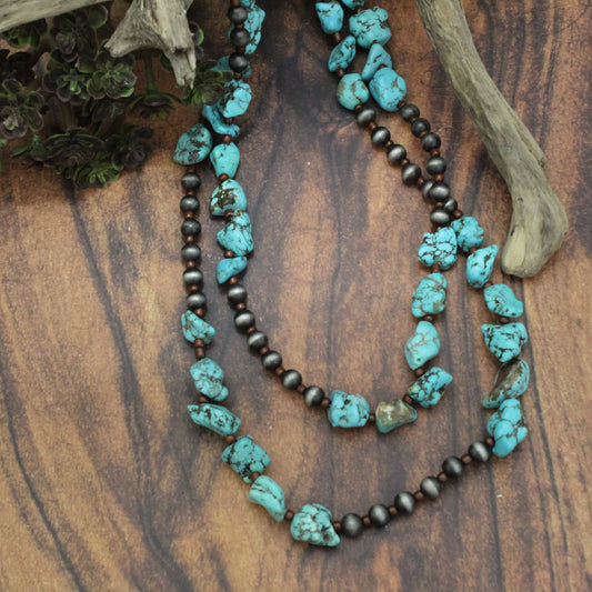 We love this piece - it is perfect by itself or layered with others. It has sections of stacked turquoise stone and then sections of dark grey beads. This alternates throughout the entire necklace. You loop it over your head and then cross once more. It hangs 62 inches long and is comfortable for everyone. Materials Turquoise resin. Beads. Copper over a white metal alloy base.