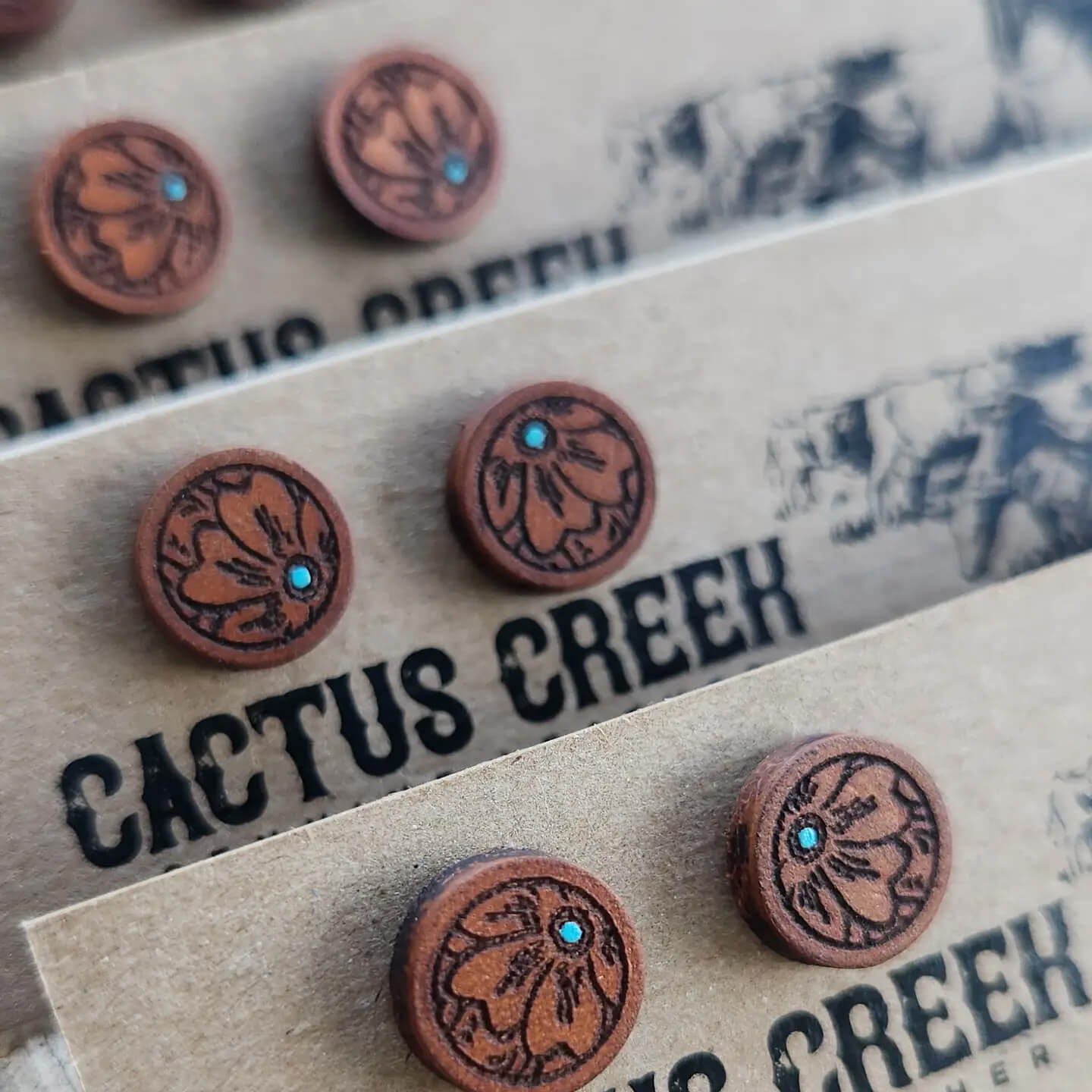 Brown leather earrings with turquoise stones on a Cactus Creek branded card.