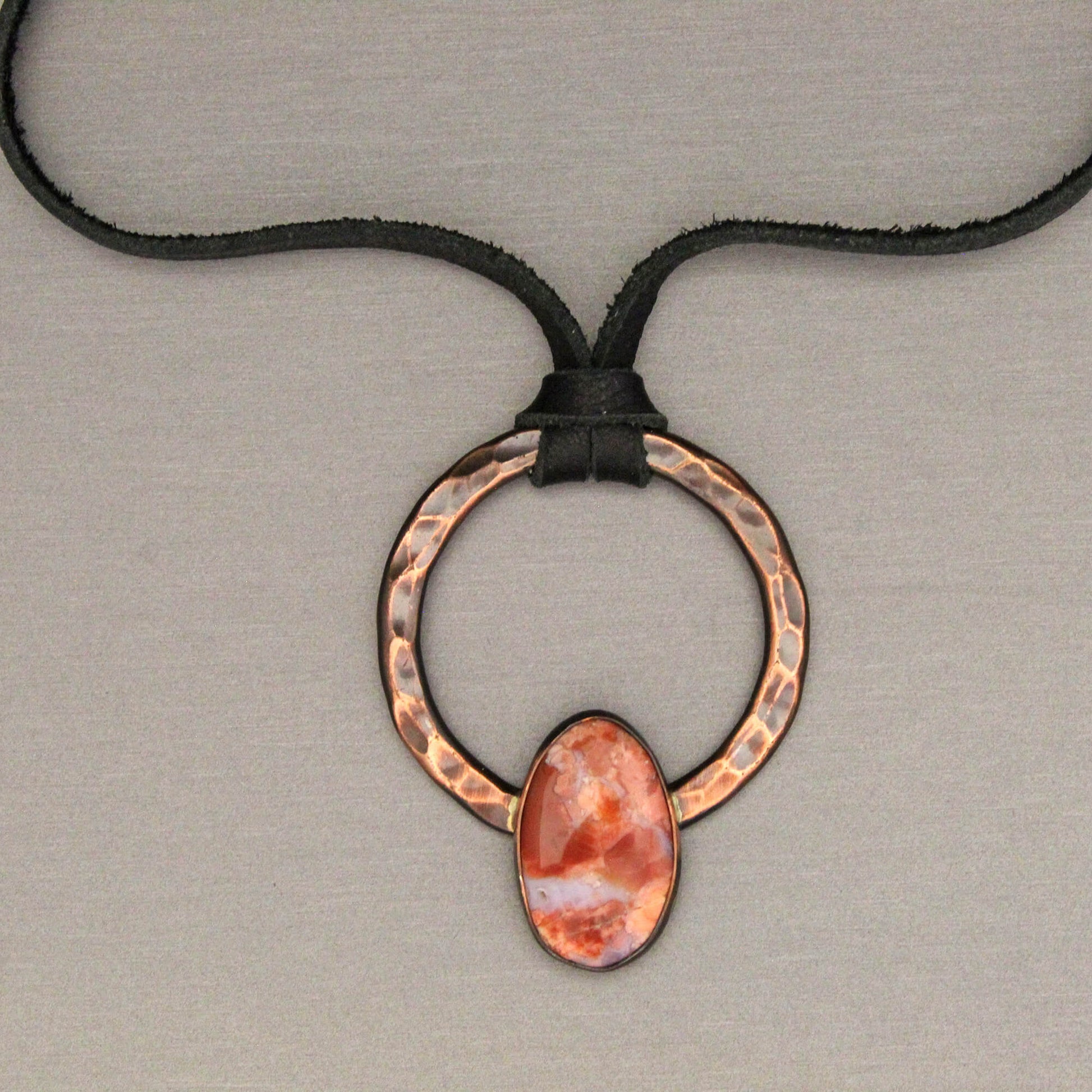 Necklace with a copper ring and cotton candy agate stone pendant on a neutral background