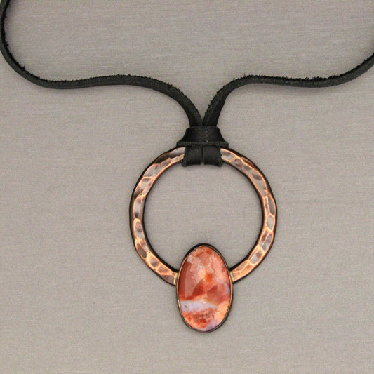Necklace with a copper ring and cotton candy agate stone pendant on a neutral background
