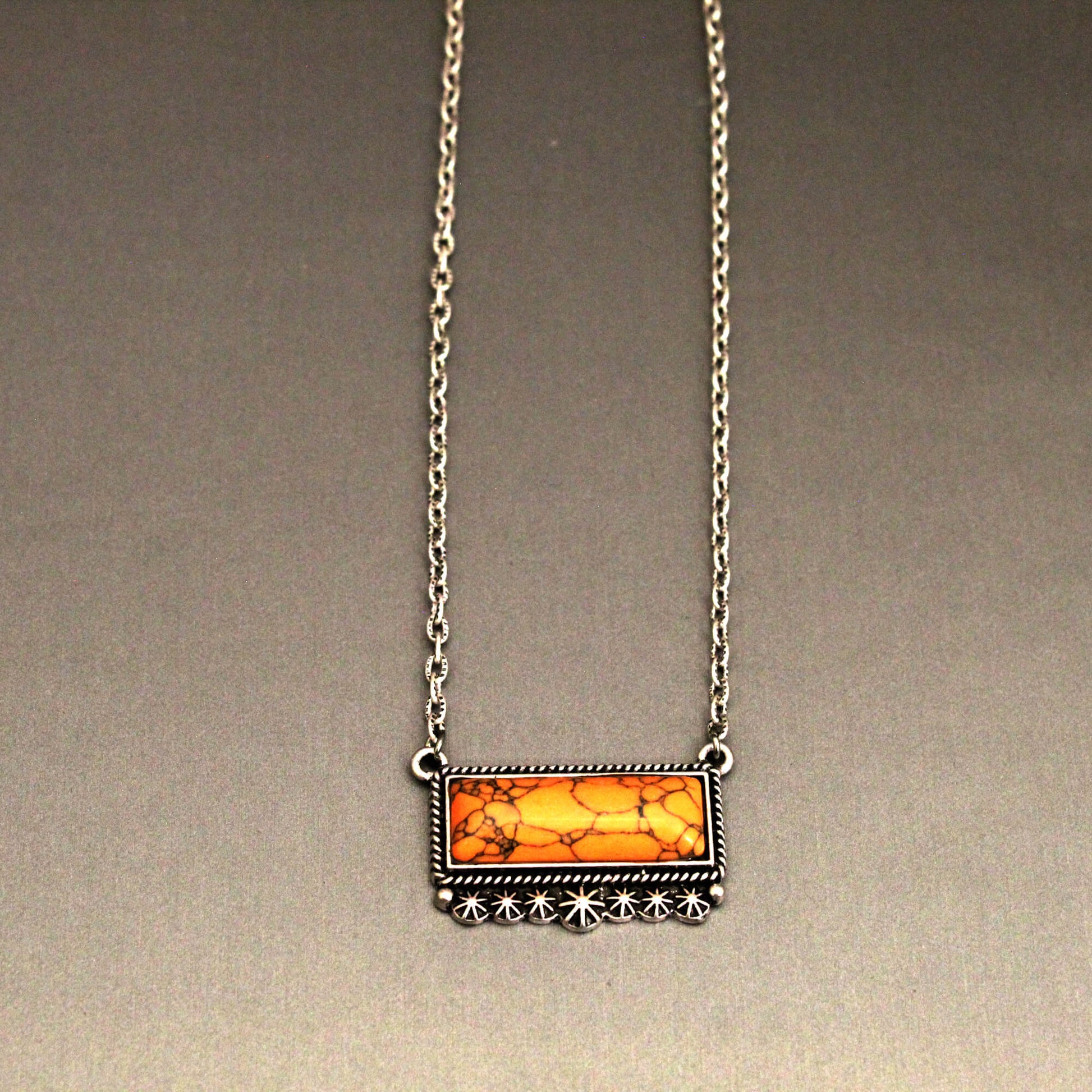 This necklace is a true statement piece that blends the rugged spirit of the American West with undeniable elegance. The vivid orange hue of the stone pendant creates an eye-catching contrast that's sure to complement your personal style. Whether you're dressing up for a night out or adding a stylish finishing touch to your everyday look, the Orange Crush Necklace will elevate your ensemble with effortless sophistication. Approx. 18" length with a secure hook clasp closure.