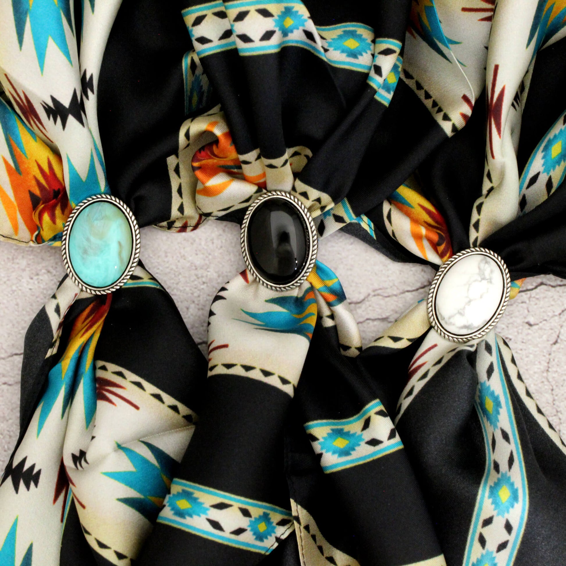 Colorful patterned scarf with decorative brooches on a textured surface