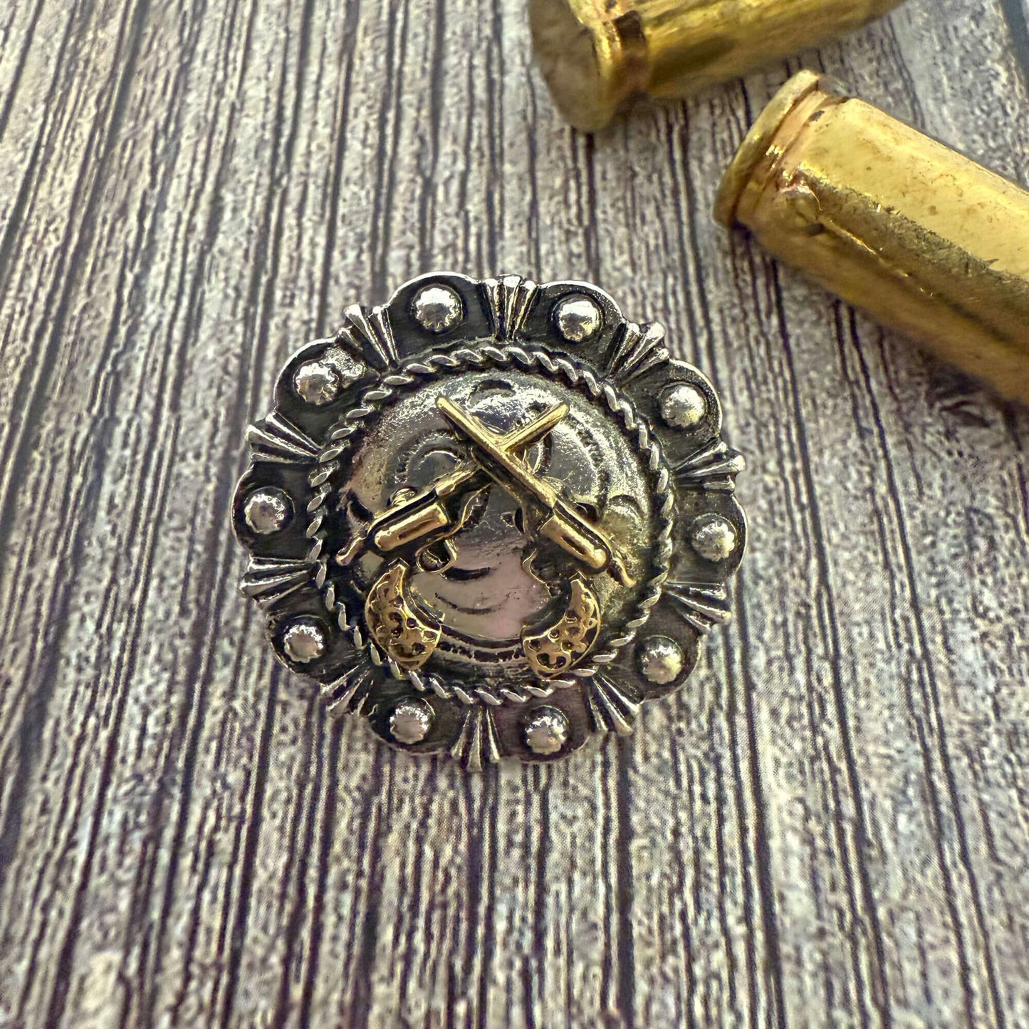 Silver and gold decorative object with a cross on a wooden surface