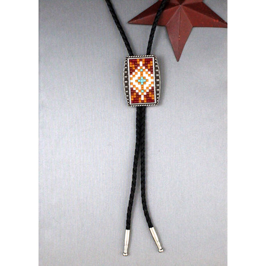A Southwestern-style bolo tie necklace featuring a rectangular beaded centerpiece with a geometric pattern in red, orange, white, and light blue, suspended from black braided cords with silver-toned metal tips, displayed on a textured gray background with a decorative brown star in the upper right.