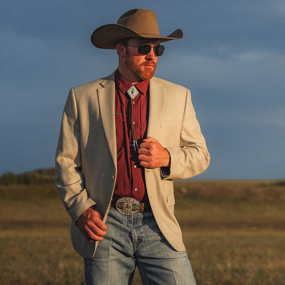 Man wearing a Santa Fe Turquoise Men's Western Bolo Tie, a stylish outfit with a cowboy hat and blazer.