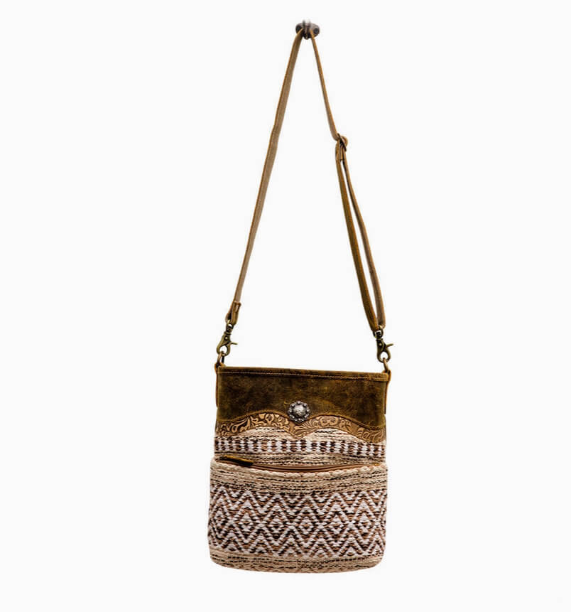 Brown leather crossbody bag with patterned bottom section on a white background