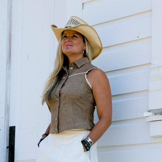 This ladies sleeveless western shirt is great for warm rodeo nights or staying cool during country swing nights. The Sierra blouse is made of yarn-dyed lightweight cotton/linen blended fabric. Armholes are finished in delicate lace and the front and black yokes trimmed in a contrast piping. The pearl snaps down the front add the perfect western touch. Made in USA. 