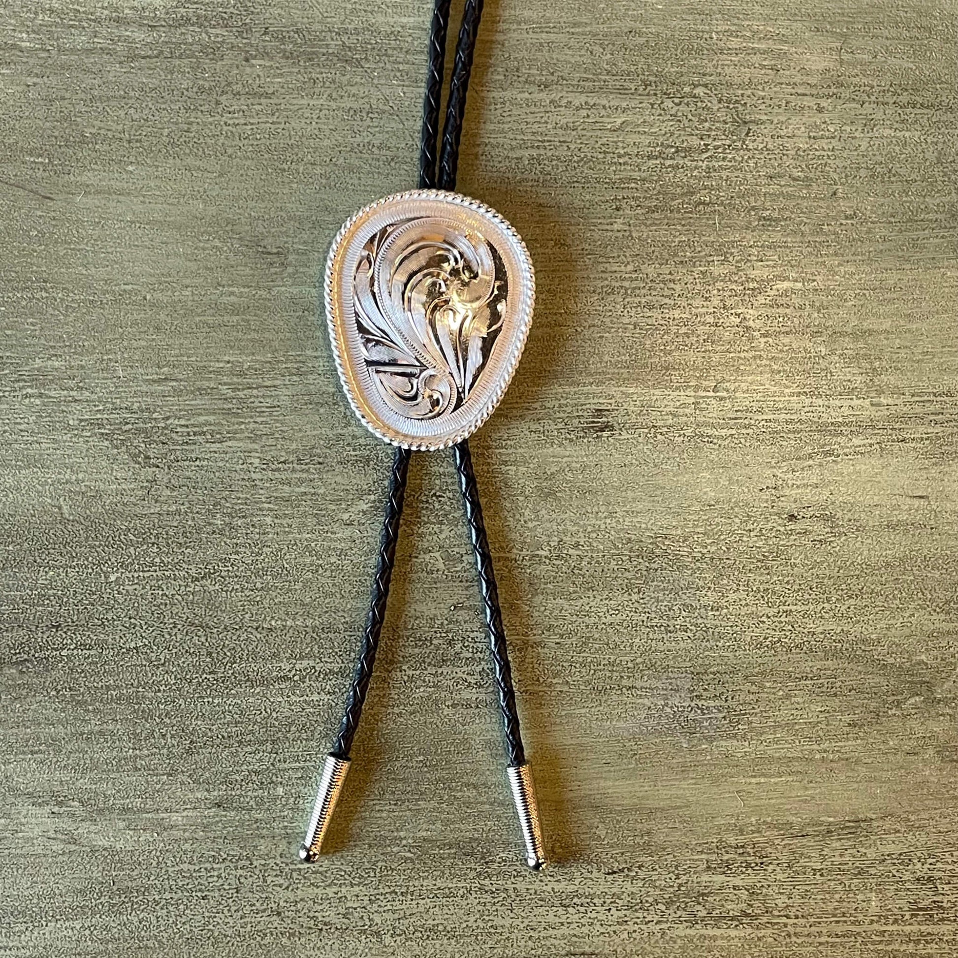 Hot and handsome cowboys keep it simple with this western bolo tie. Stylish silver oval bolo, great for special events like a wedding or dress up that shirt for Cowboy Church! German Silver plated bolo measures; on a black braided cord 36” long.