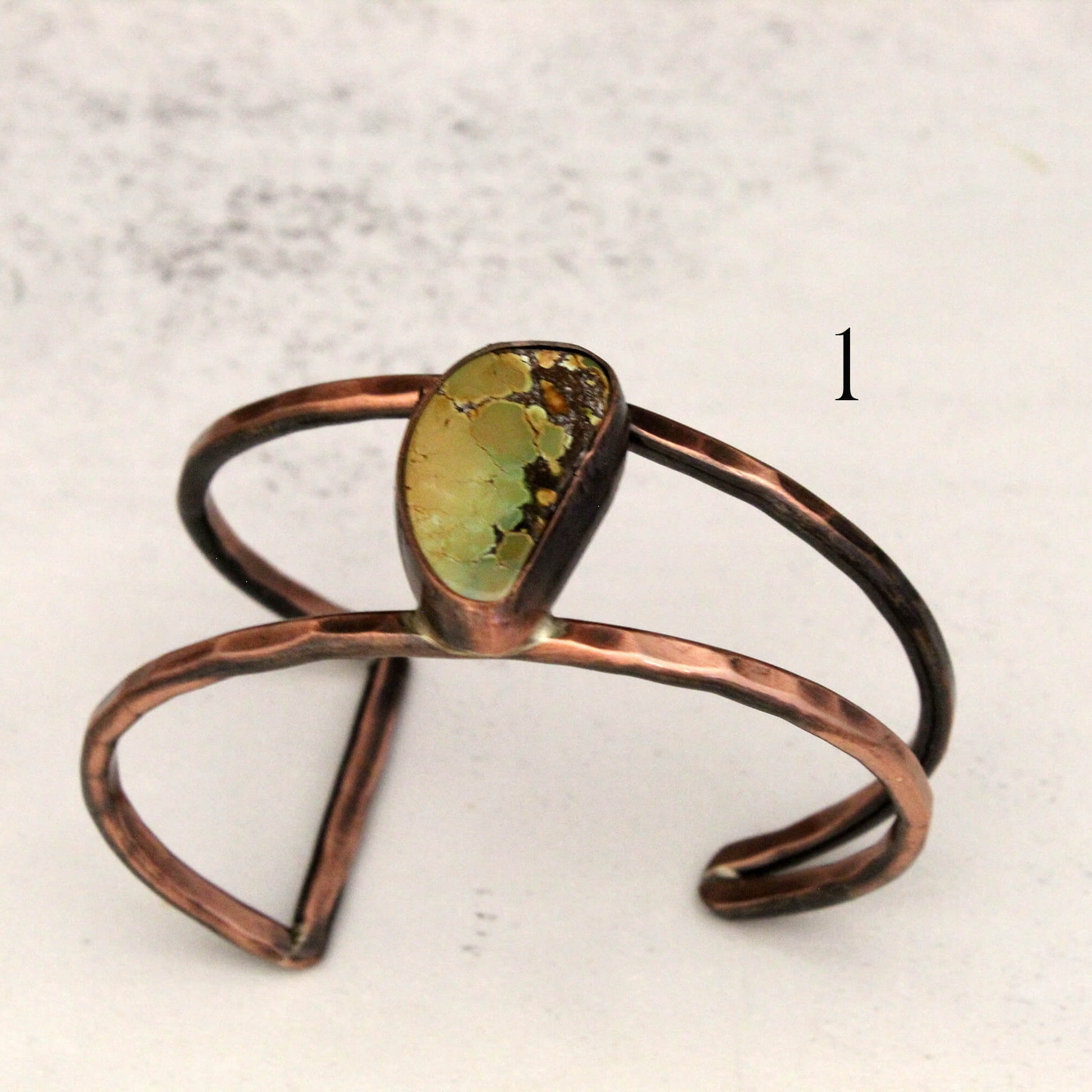 Copper bracelet with a green stone on a light background