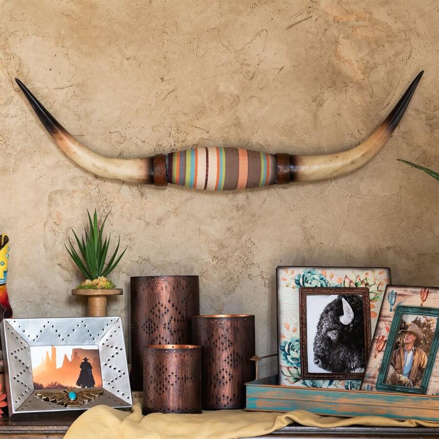 An elegant rustic wall accent for your home, this longhorn wall sculpture is made from durable resin that’s been hand-painted and polished for authenticity. Its center features a Serape-striped felt wrapper for a distinct Southwestern touch. At the back is an embedded keyhole hardware for easy and secure installation. Dimensions 9"W x 33"L Made of Resin