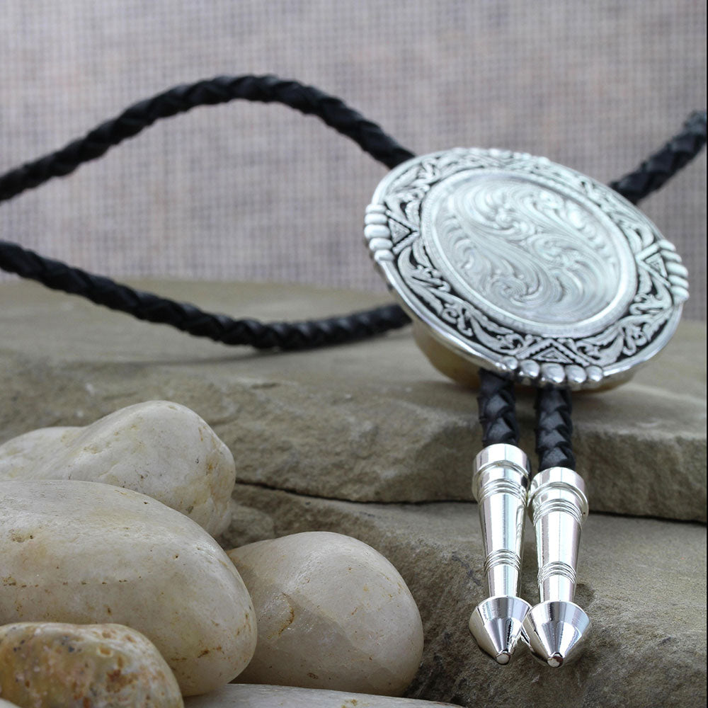 Tall oval slide features silver engraved in traditional western bright cut, framed by antiqued silver filigree and geometric accents in old southwestern style. Silver wire trim with sets of five beads at the top and bottom and each side. The black braided leather cord is nicely weighted with two silver arrow pointed tips. 36" Black Leather Cord with Silver Tips. Slide Measures 2.25" X 2". Made un USA