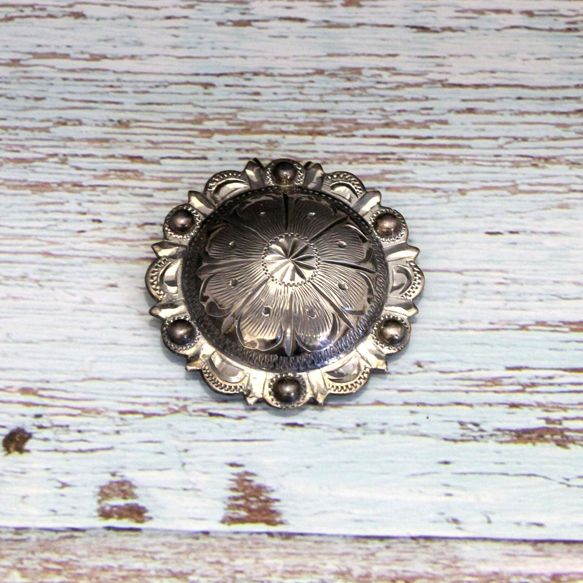 Decorative silver barrette with intricate design on a wooden surface