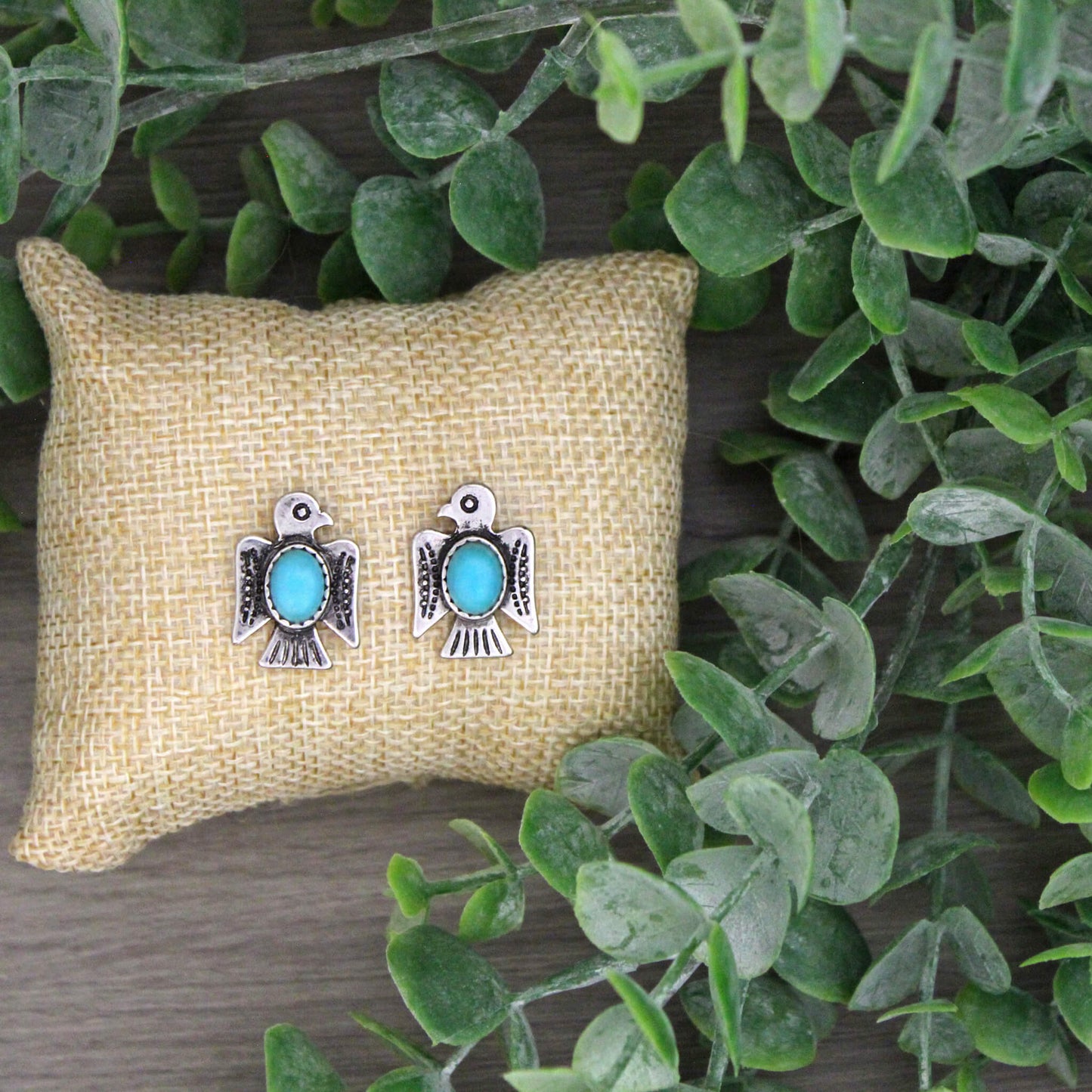 Western inspired thunderbird shaped stud earrings. Timeless stamped silver thunderbird earrings featuring a turquoise oval-shaped stone. The perfect western accessory. Measures 3/4" by 5/8"