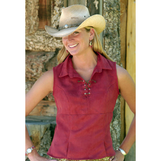 Woman in a terra cotta suede sleeveless top with a brown lace-up detail, wearing a cowboy hat outdoors.