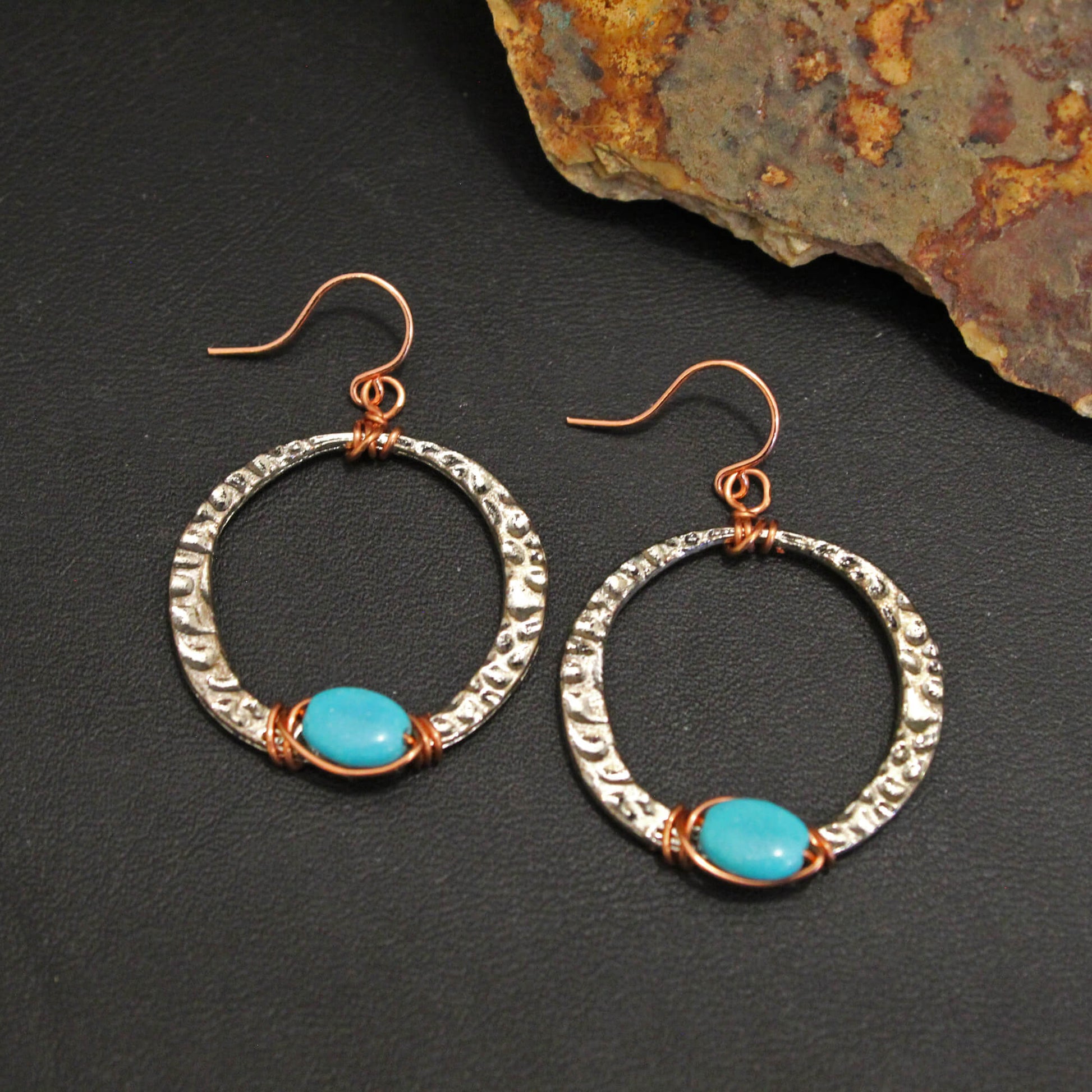 Silver hoops with copper wire wrapped with a turquoise bead and measures approx. .1″ from the base of hypo allergenic ear wires. Each pair has its own unique features and Made in USA.