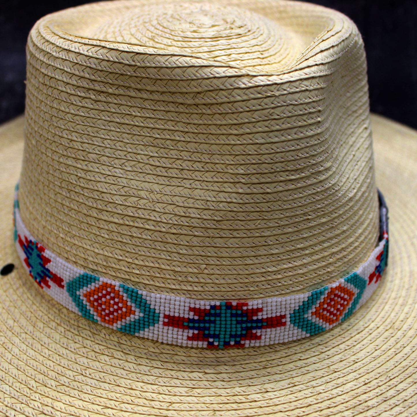 Add a splash of vibrant color and flair to your hat with this beaded hatband. With its intricate design of bright blues, reds and oranges against a crisp white background, this accessory makes a bold fashion statement.