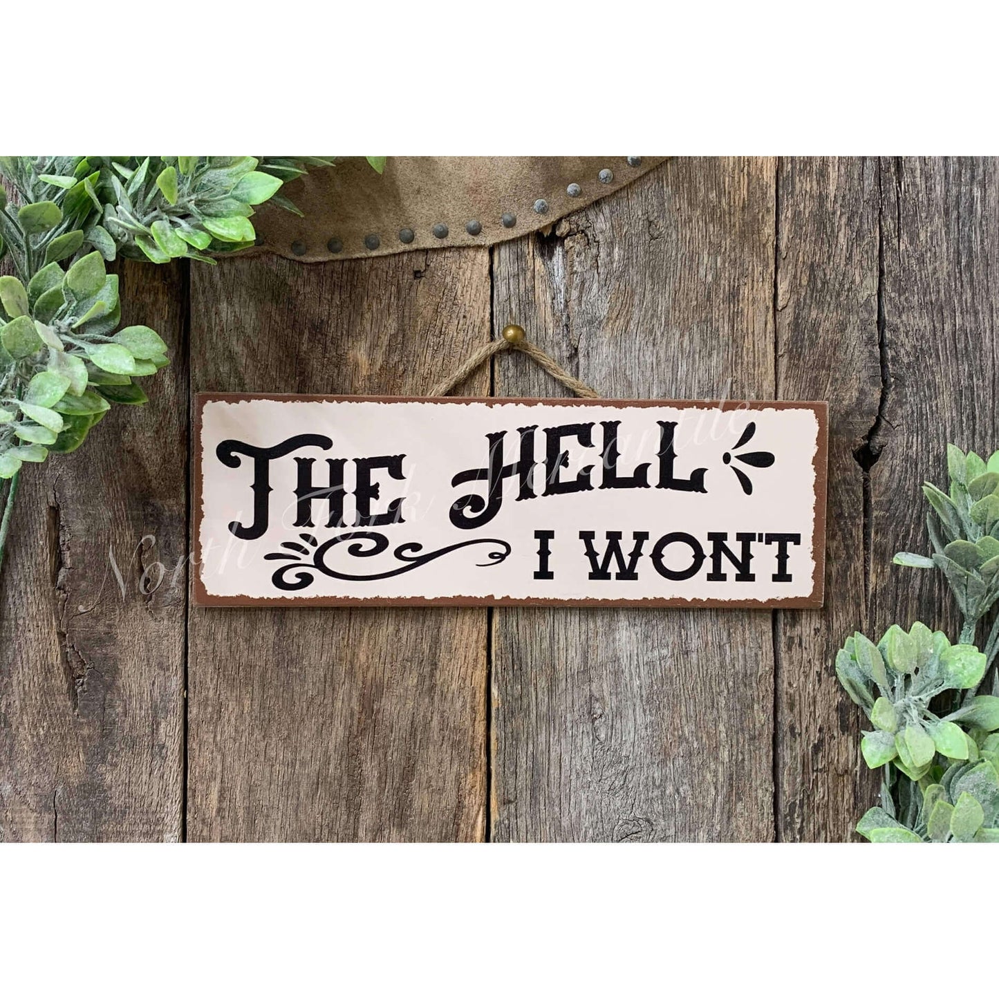 Decorative sign with text 'The Hell I Wont' on a wooden background