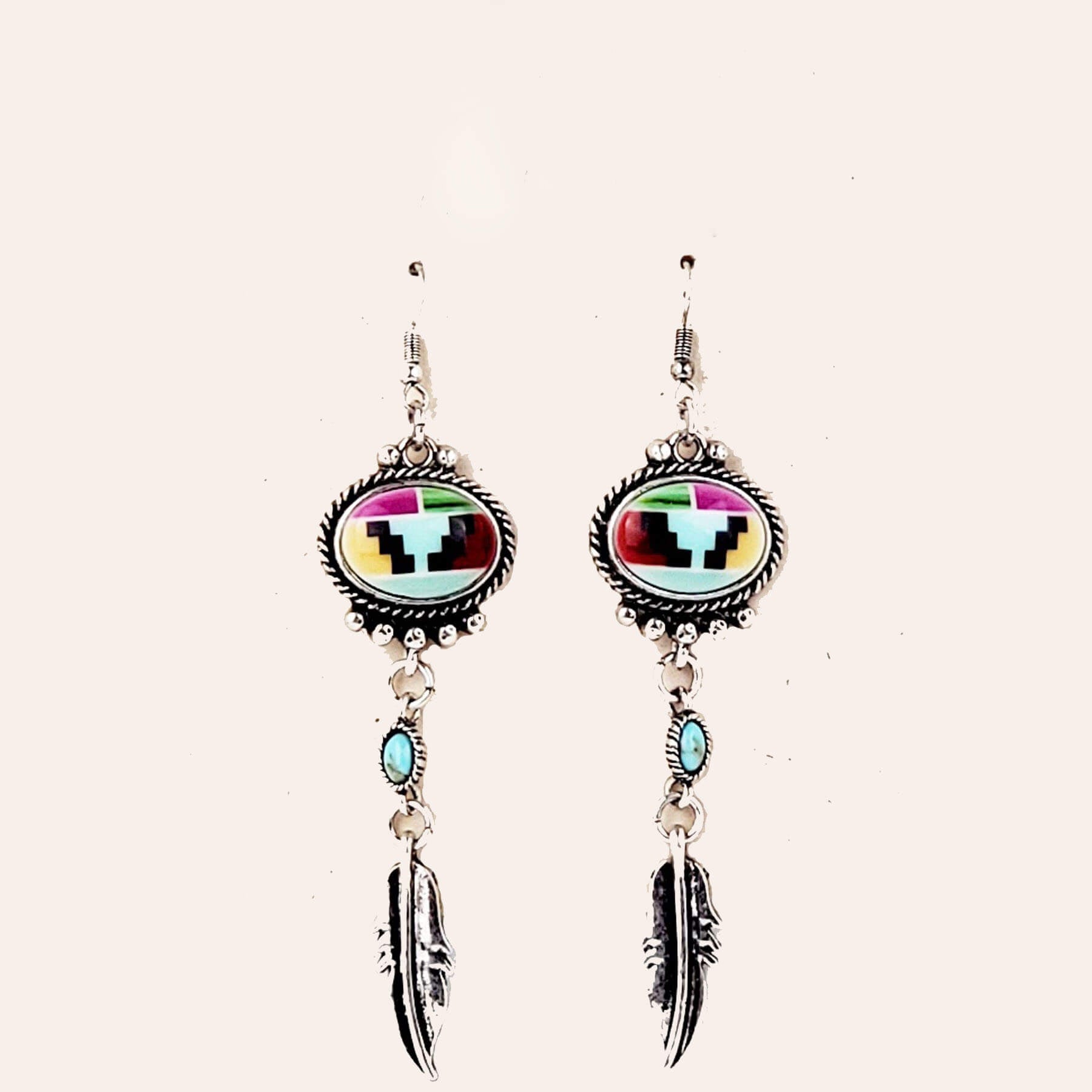 Striking earrings to add some pizzazz to any outfit. A Native American inspired design surrounded by an embellished oval frame with a silver feather. Dangle-style earrings measure 3″ from bottom of hypoallergenic ear wire to bottom of feather.