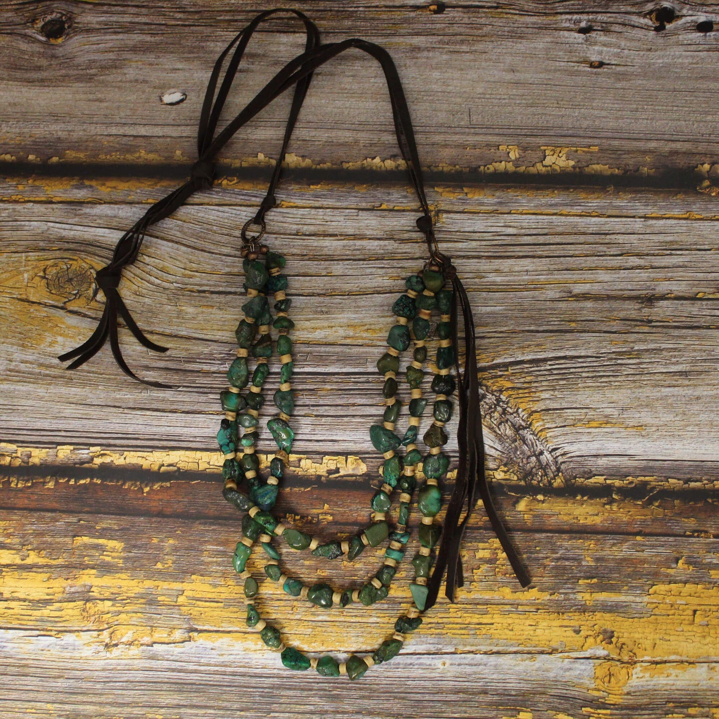 Command attention with the Triple Long Strand Turquoise and Wood Necklace. This boho-chic beauty features three tiers of genuine green turquoise nuggets and natural wood beads on braided brown leather.