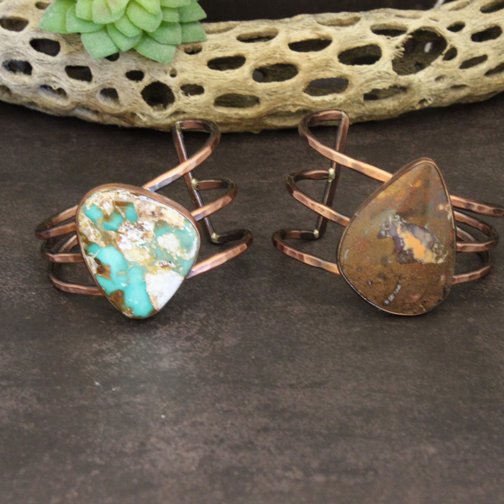 Two copper rings with natural stone inlays on a dark surface.