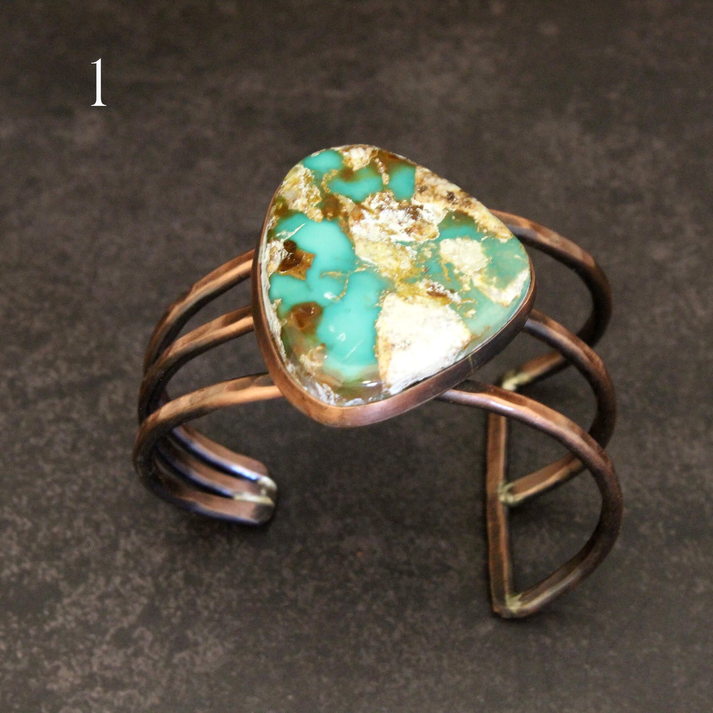 Turquoise stone ring with bronze wire wrapping on a dark background