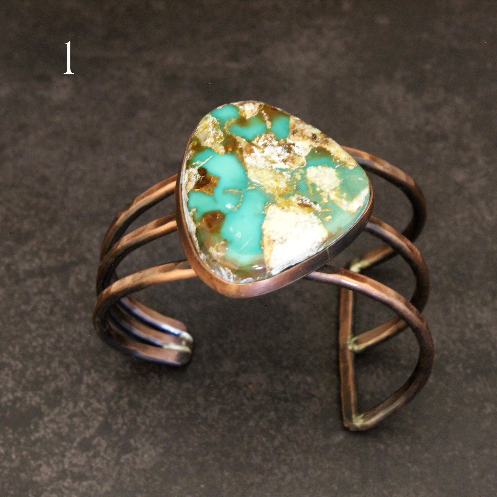 Turquoise stone ring with bronze wire wrapping on a dark background