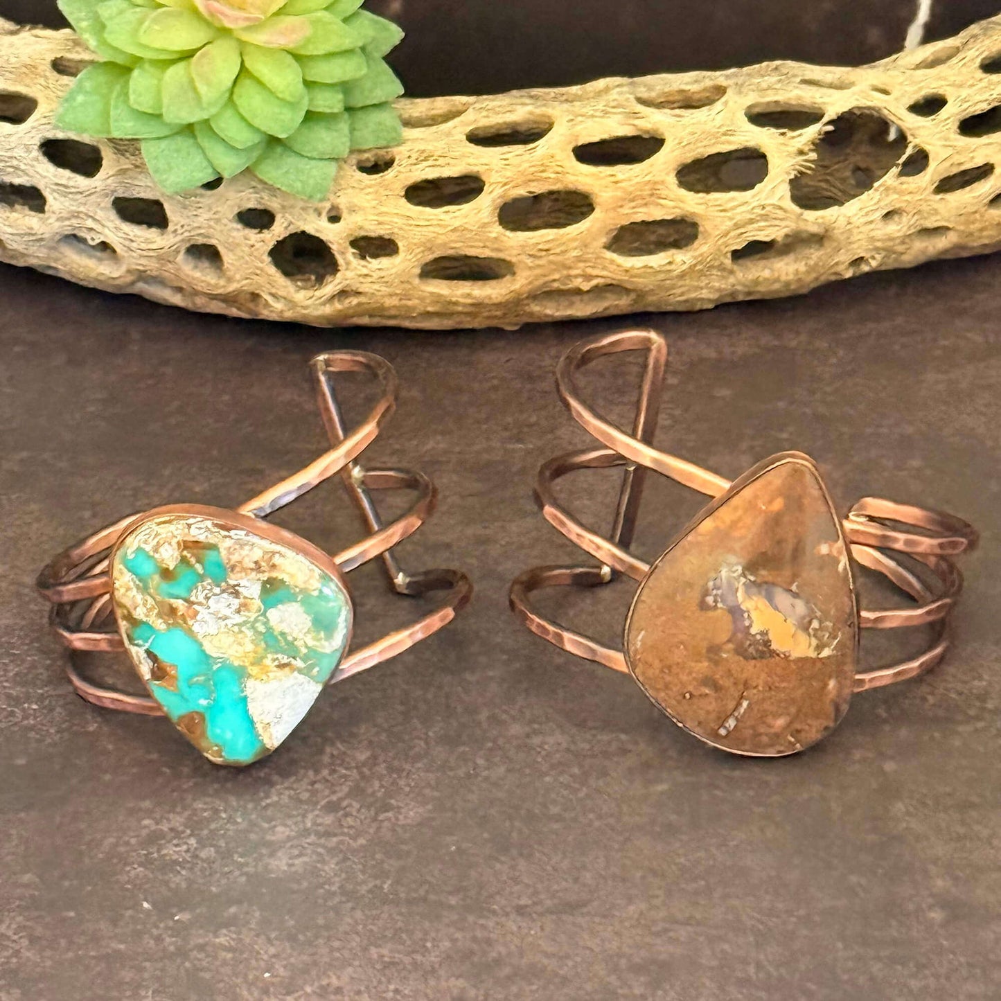 Two copper rings with stone inlays on a textured surface.