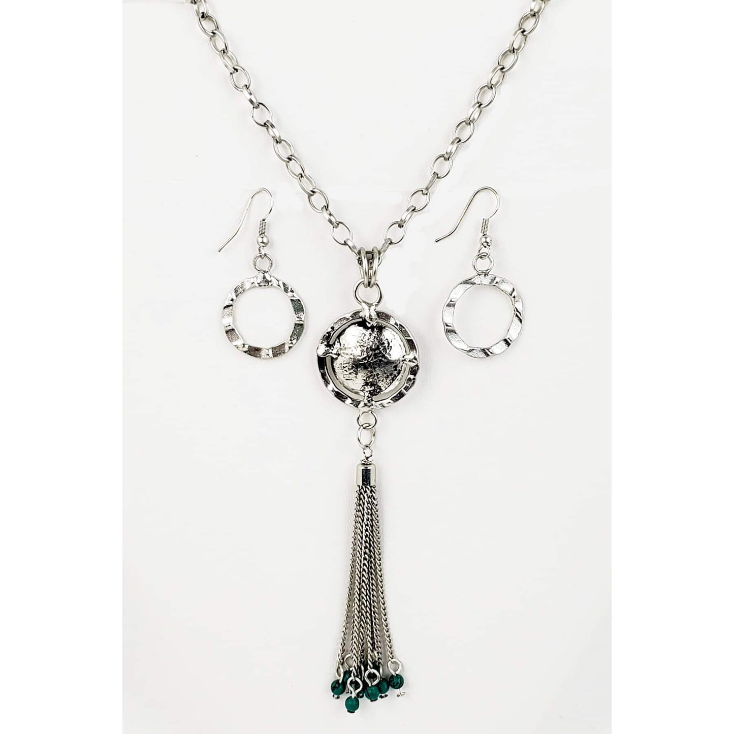 Silver large link chain holds a pendant with chain fringe and mag turquoise bead accents. Necklace measures 35″ with lobster claw clasp and extension chain. Hammered circle earrings on hypoallergenic ear wires