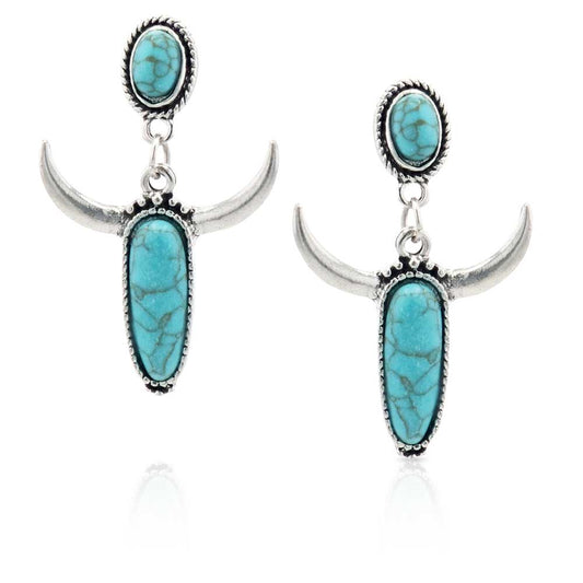 Featuring the classic Southwestern motif of a steer skull and turquoise the Turquoise Steer Attitude Earrings are an innovative twist. Hanging from a circular turquoise stone wrapped in smooth and roped silver and black paint are oblong teardrop shapes that allude to a steer skull. Silver-toned horns come off the long turquoise stone surrounded by silver-tone roping. Hanging from a post-back wire these earrings are an adorable addition to any wardrobe.