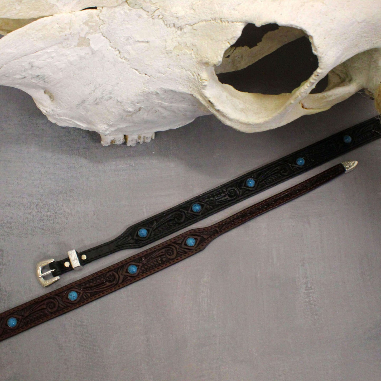These western leather hatbands are beautifully embossed with a design and striking turquoise studs that add a vibrant touch of flair to any hat. With a secure silver buckle closure, it fits most hats comfortably and measures 3/4" wide, making it the perfect accessory for cowboys and cowgirls alike.