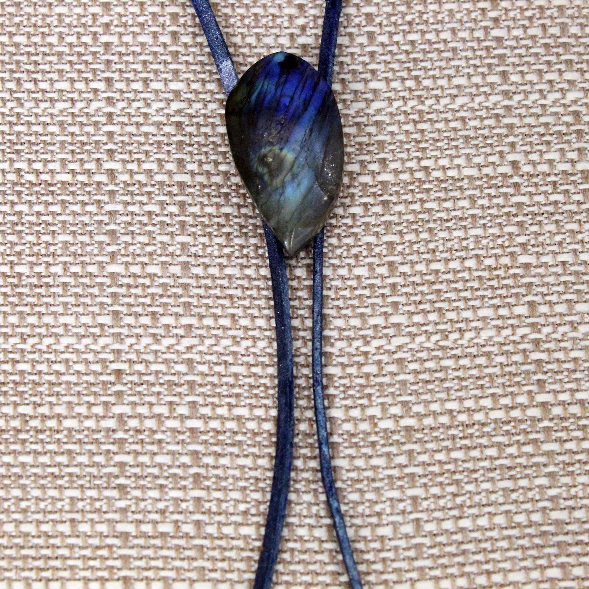 Necklace with a dark blue pendant on a beige textured background