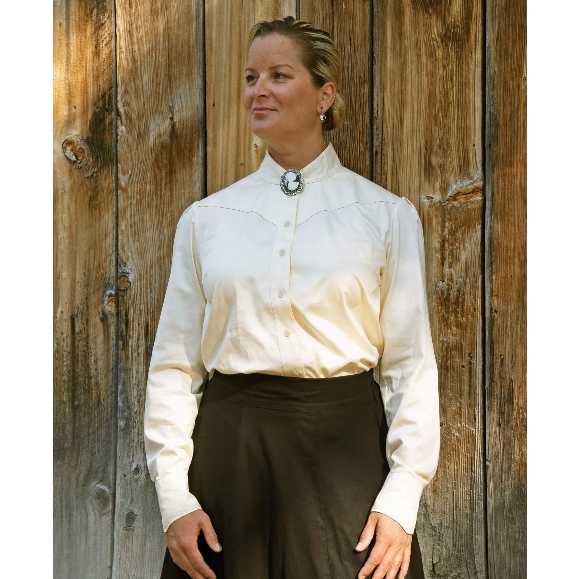 Our new favorite Cattle Kate blouse has a collar that buttons for a perfect high Victorian neckline. Collar can highlight a vintage brooch or classy up-do.  The angled yoke and cuffs have delicate lace to add a contemporary take on the Victorian style blouse. A unique tuck in the back gives just the right fit. 100% Cotton Ivory Sateen. Made in USA.