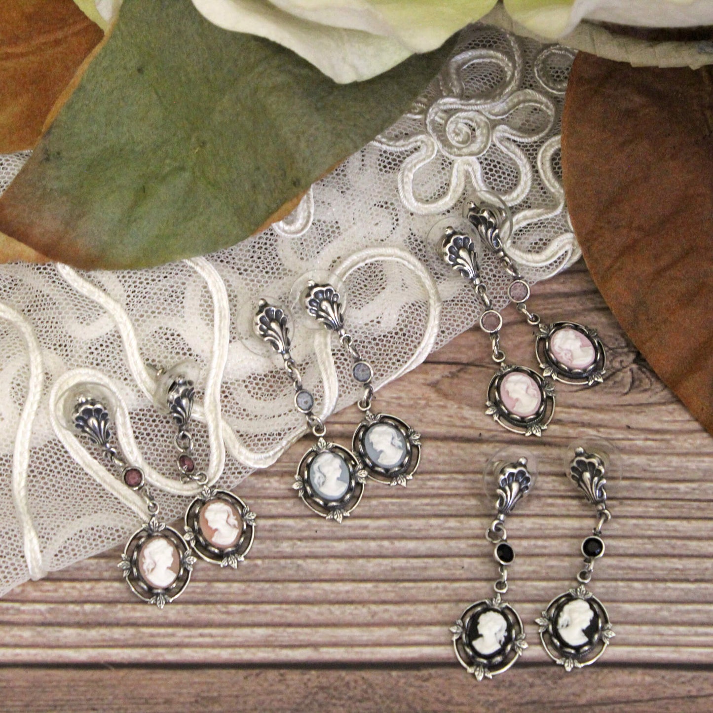 Silver earrings with pink stones on a lace and wooden surface