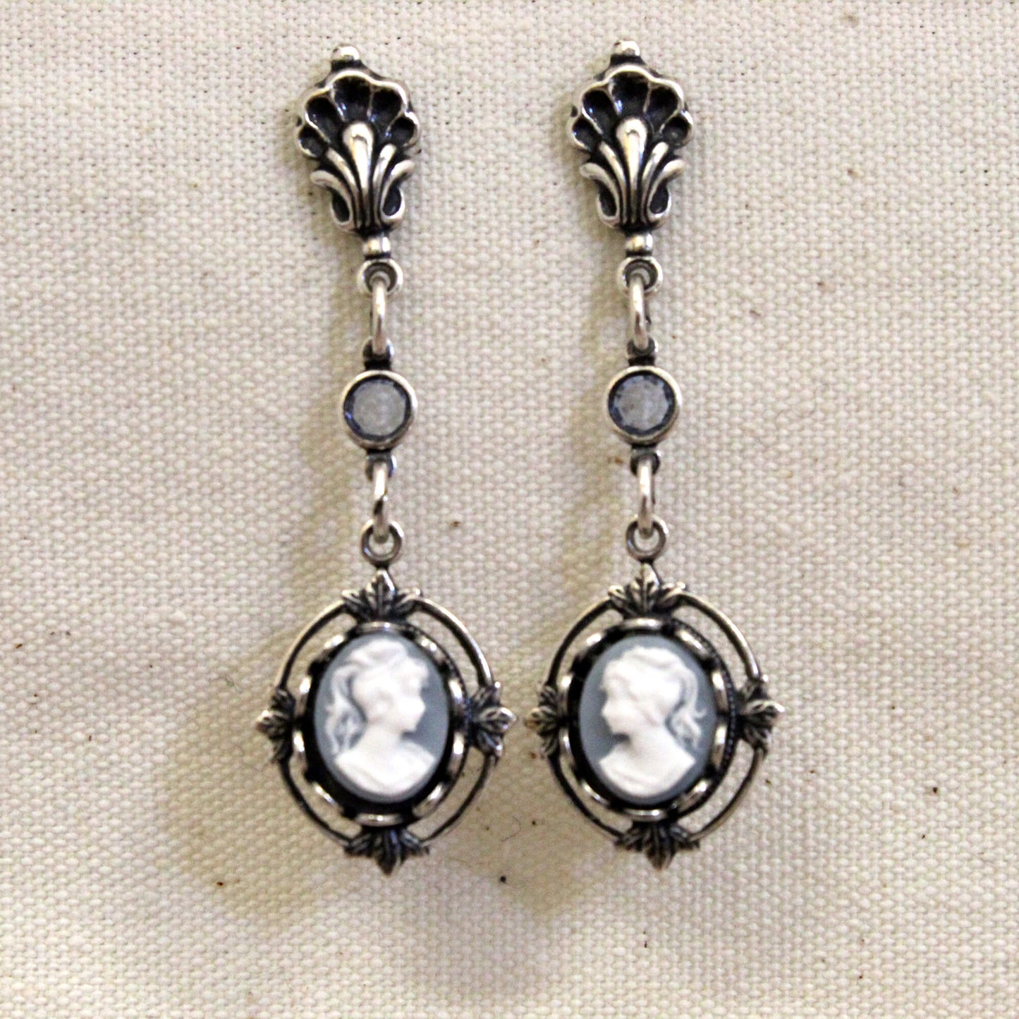 Pair of silver earrings with cameo designs on a beige background