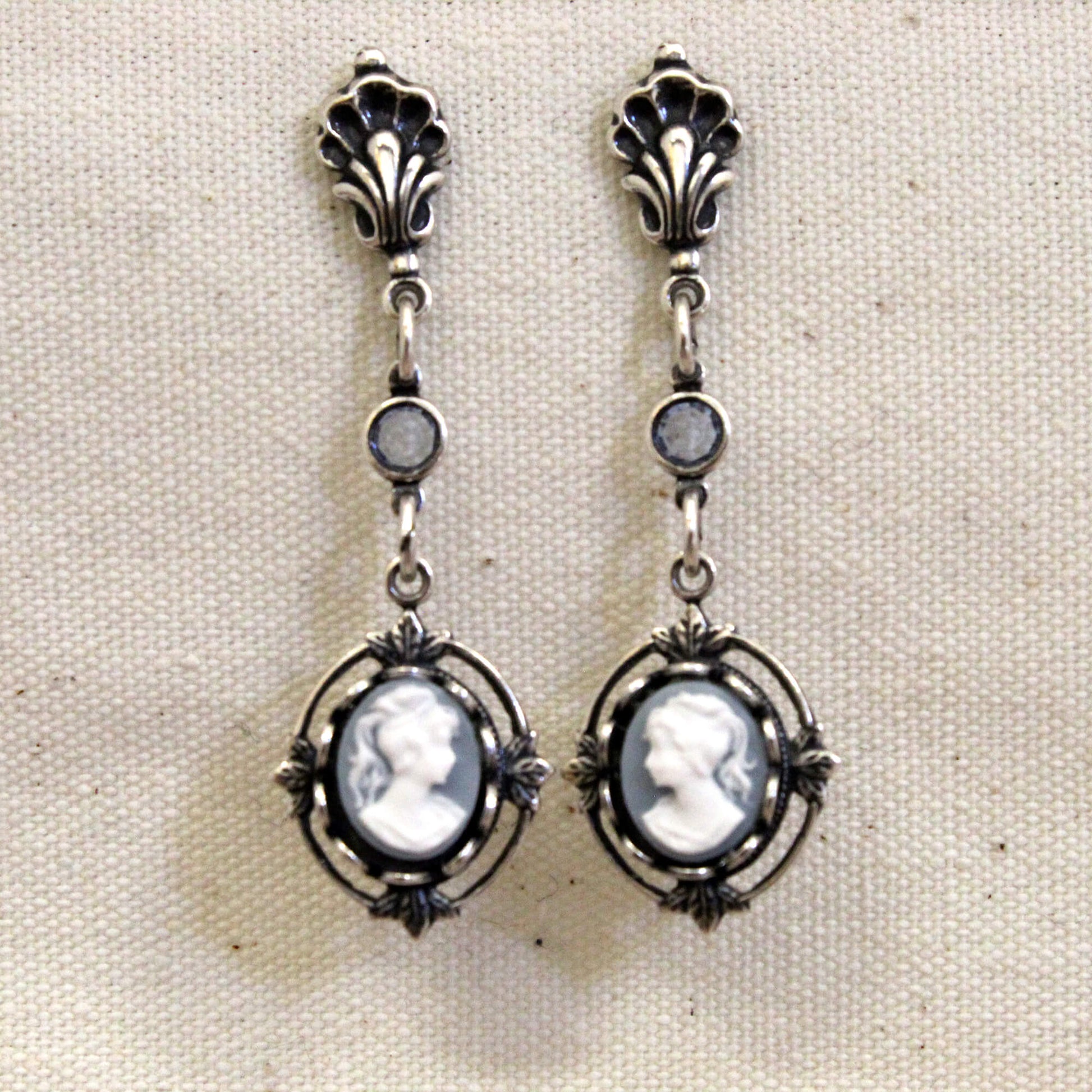 Pair of silver earrings with cameo designs on a beige background