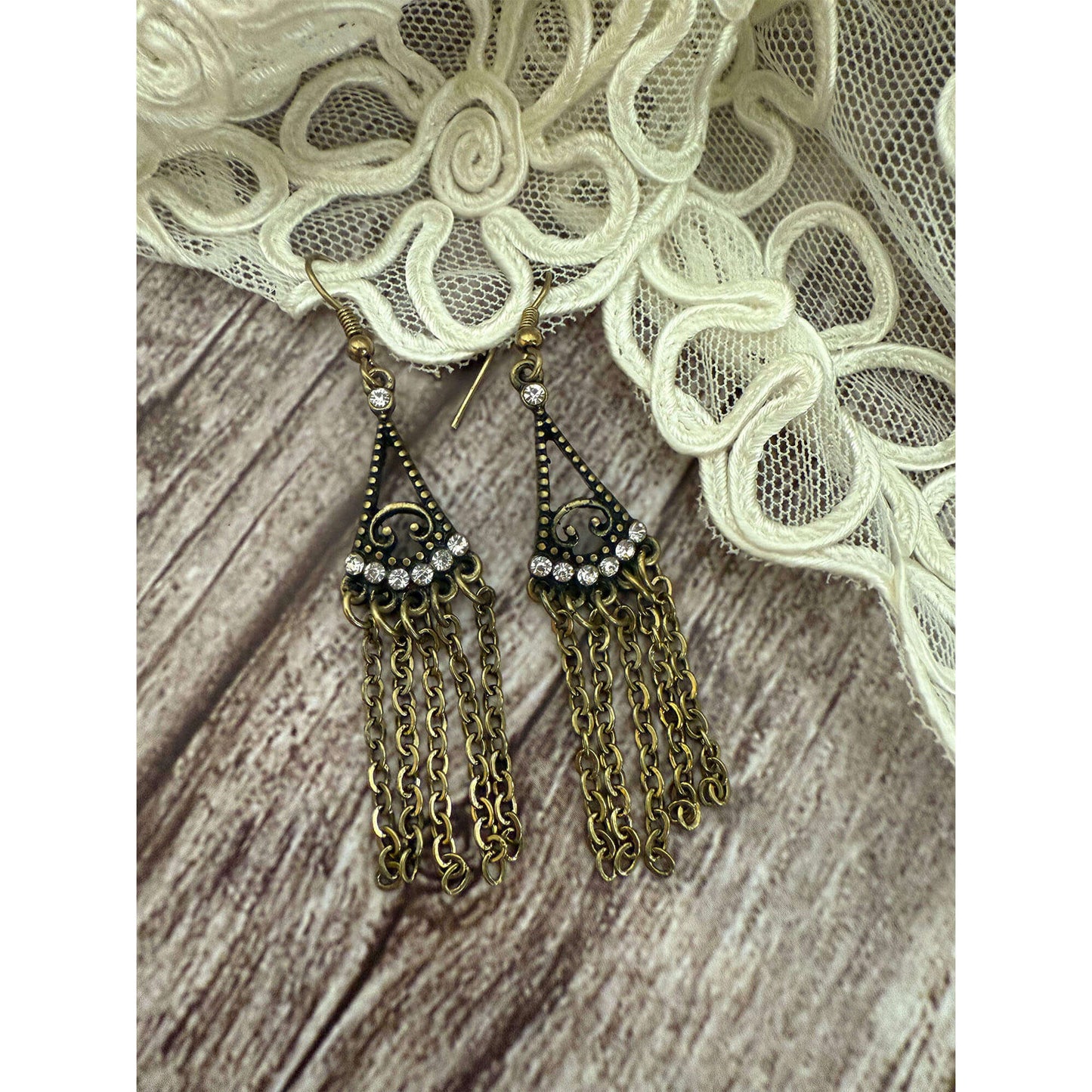 Pair of gold chain earrings with tassels on a lace fabric background