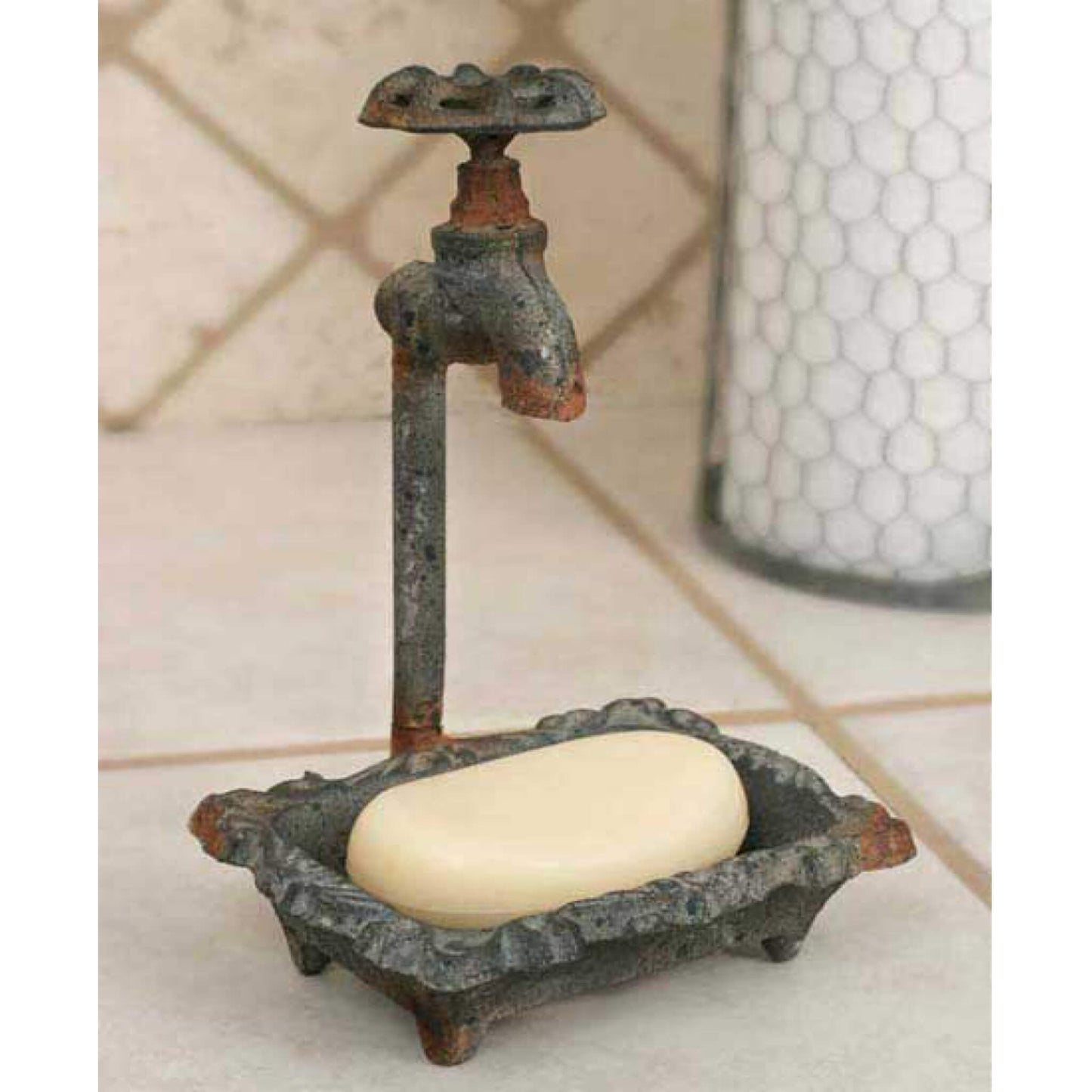 Cast metal soap dish features a floral pattern on the base. Measures 6" wide and 8½" tall. Textured dark grey finish with rust-colored accents. Water spout knob is cast and does not spin.