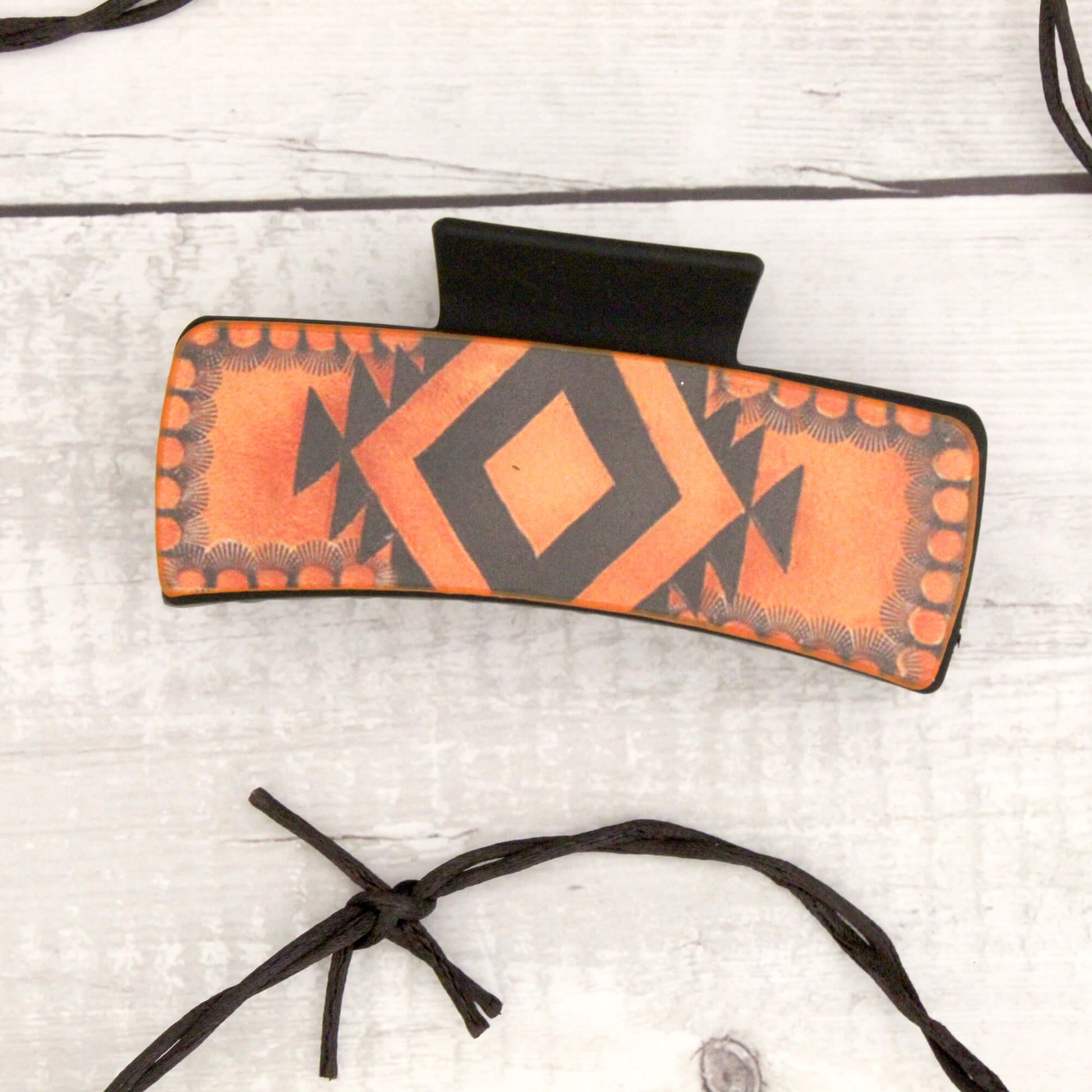 Orange and black patterned hair clip on a light gray background